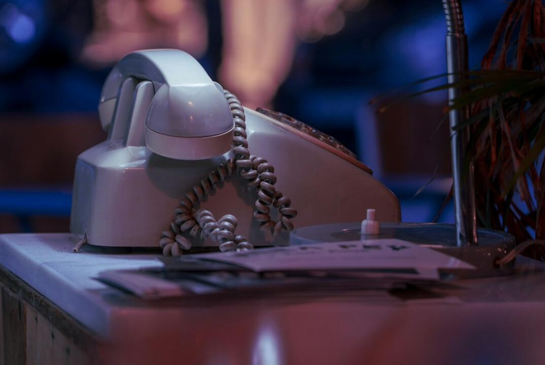 Bright minimalist office desk with a telephone, notebook and pen